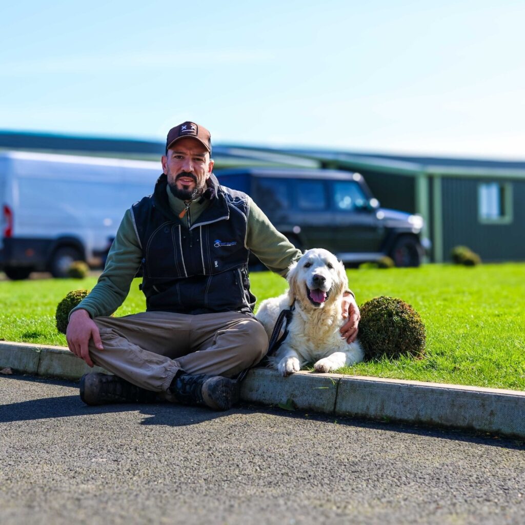 Taz sitting with a Golden Retriever outside Heronswood